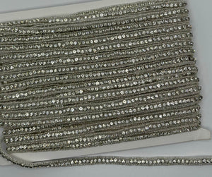 Beaded and rhinestone yardage displayed on a spool.
